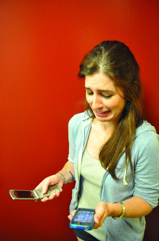 Colleen looks with horror at the iPhone as she grips her lifeless flip phone, which remains useless and abandoned in her right hand. (Mario Weddell/The Observer)