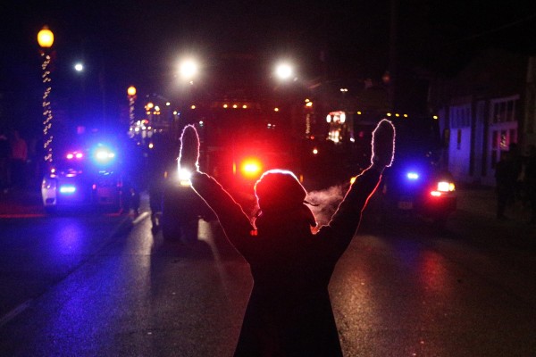 A+protester+raises+her+hands+in+the+street+as+police+use+tear+gas+to+try+to+take+control+of+the+scene+near+a+Ferguson+Police+Department+squad+car+after+protesters+lit+it+on+fire+on+Tuesday%2C+Nov.+25%2C+2014%2C+in+the+wake+of+the+grand+jury+decision+not+to+indict+officer+Darren+Wilson+in+the+shooting+death+of+Ferguson%2C+Mo.%2C+teen+Michael+Brown.+%28Anthony+Souffle+%2F+Chicago+Tribune%2FTNS%29