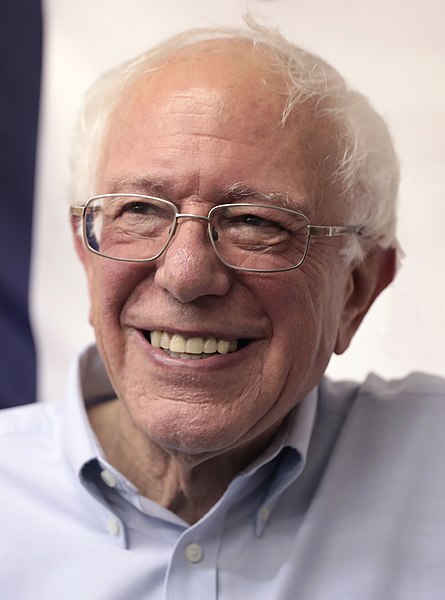 Up-close shot of Bernie Sanders smiling in glasses and a white collar shirt