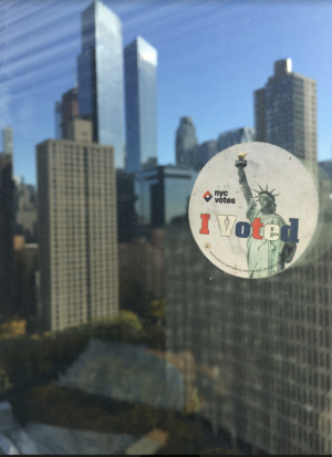 An I Voted sticker stuck to a window in McKeon Hall overlooking midtown Manhattan