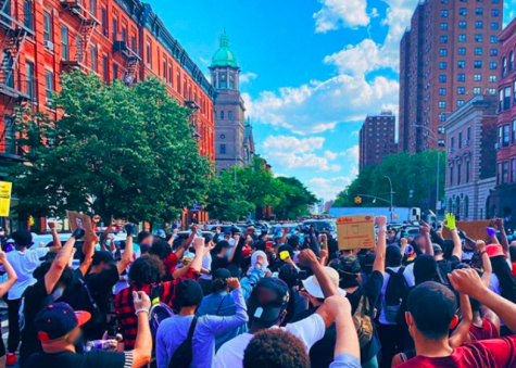a crowd protests in the Bronx with fists raised