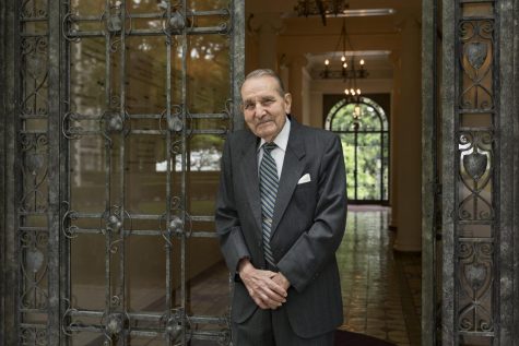 Cammarosano standing in a suit in tie in front of a glass door