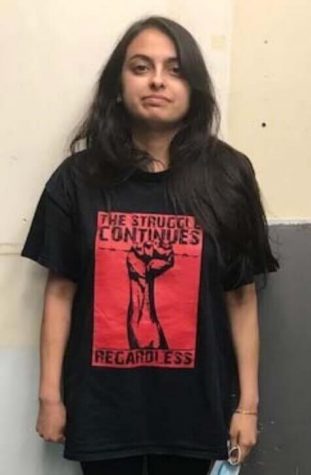 Mugshot of Rahman after arrest wearing a black shirt with a red graphic of a raised fist reading "The Struggle Continues Regardless"