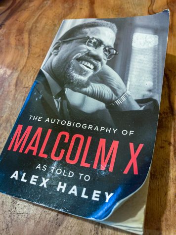 A photo of The Autobiography of Malcolm X as Told to Alex Haley on a table. The cover portrays Malcolm X smiling with his hand on his face.