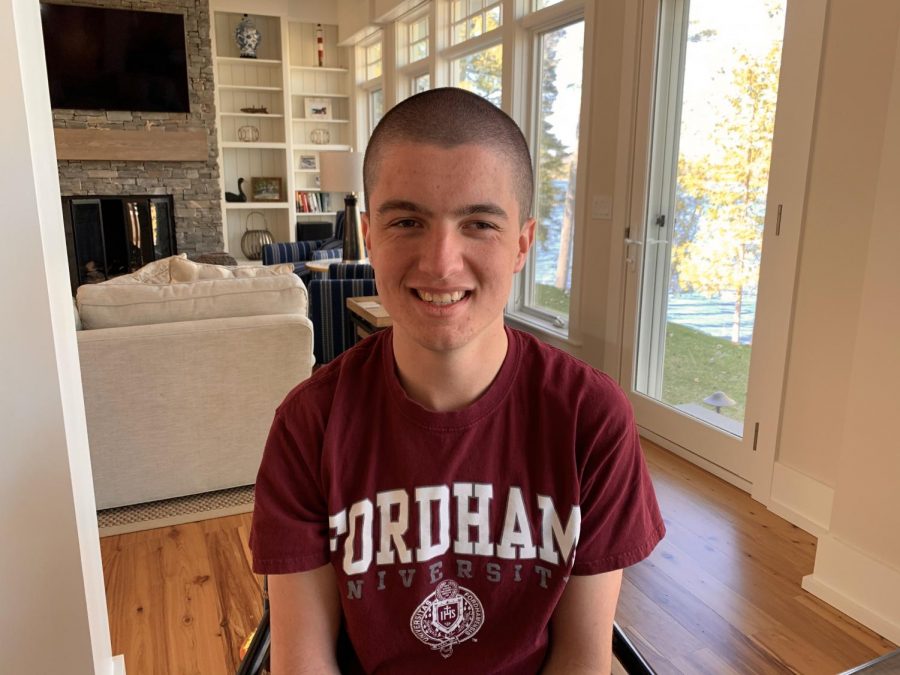 photo of male freshman student sitting in his home with a fordham t-shirt