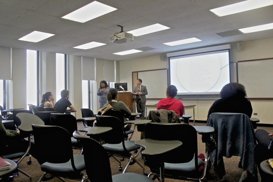 Fordham classroom with students sitting at desks facing a whiteboard, photographed from the back