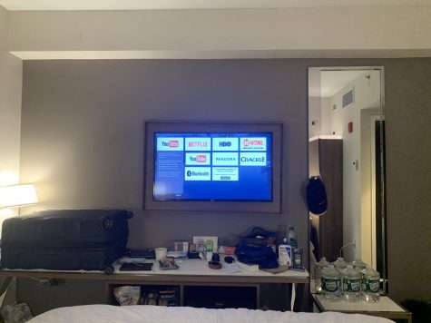 a hotel room, including a TV with Netflix, Crackle and YouTube icons on it, water bottles, a table and a couch