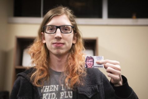 a transgender student holding their ID up for the camera while covering their dead name with their finger