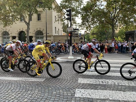 group of cyclists riding on a cobblestone street in the tour de france
