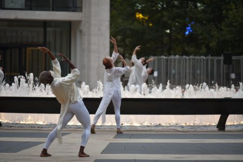 two dancers dressed in white in front of a fountain for table of silence