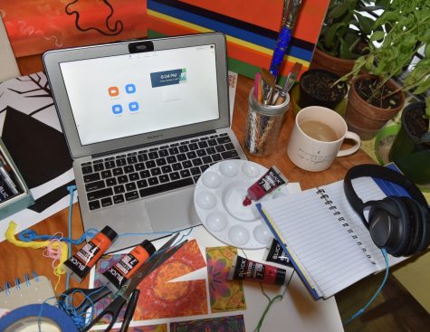 a laptop amongst art supplies at a visual arts students desk