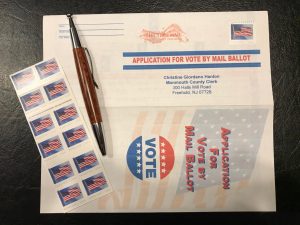 an application for mail-in voting with a pen and stamps