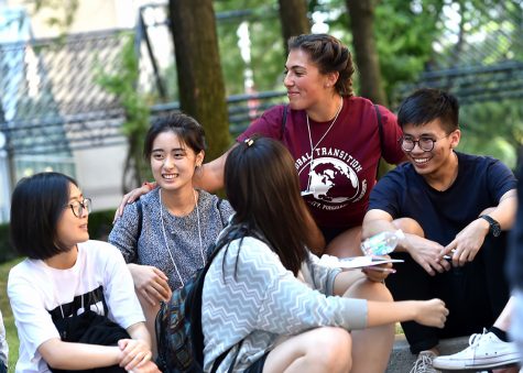 a group of international students smiling as they sit in a group on the Outdoor Plaza