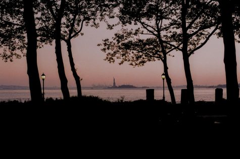 Park at sunset with Statue of Liberty standing across the water