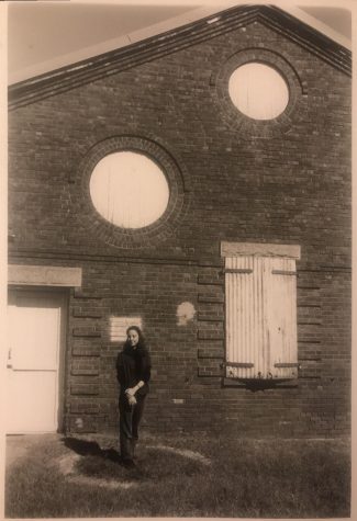 In black and white, woman stands in front of old building