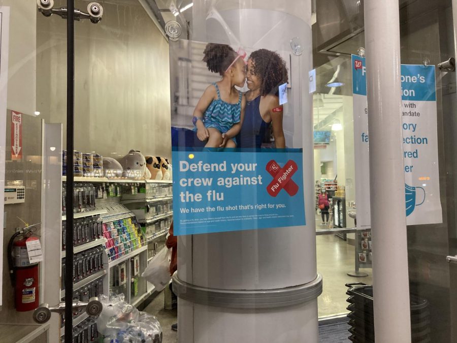 blue poster on a pole with a mother and daughter on it that reads, Defend your crew against the flu. We have the flu shot thats right for you.