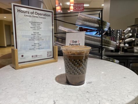 a to-go drink on a counter in front of a sign with the modified hours at argo tea, one of the limited dining locations