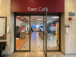 the doorway of the ram cafe dining location, with a red sign on top saying ram cafe and one of three glass doors open