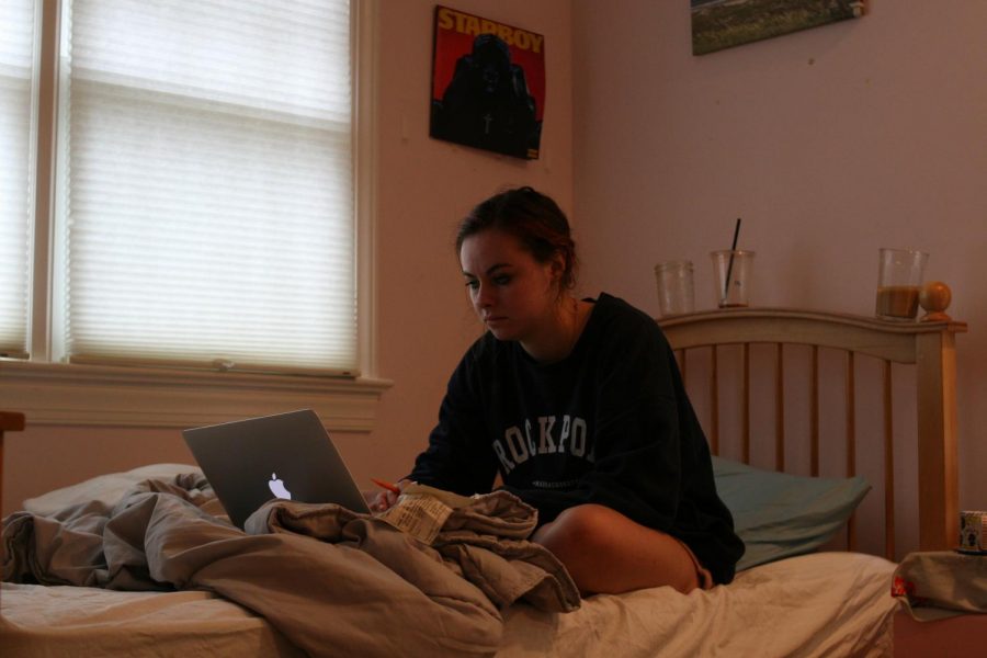 girl sitting on a bed looking at a laptop screen