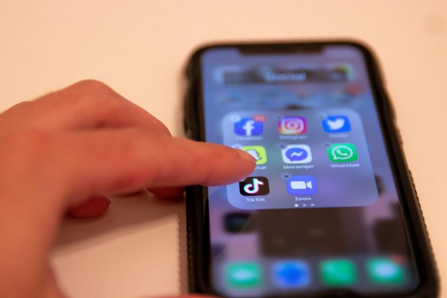 a finger holding down the tiktok app on an iphone to delete it