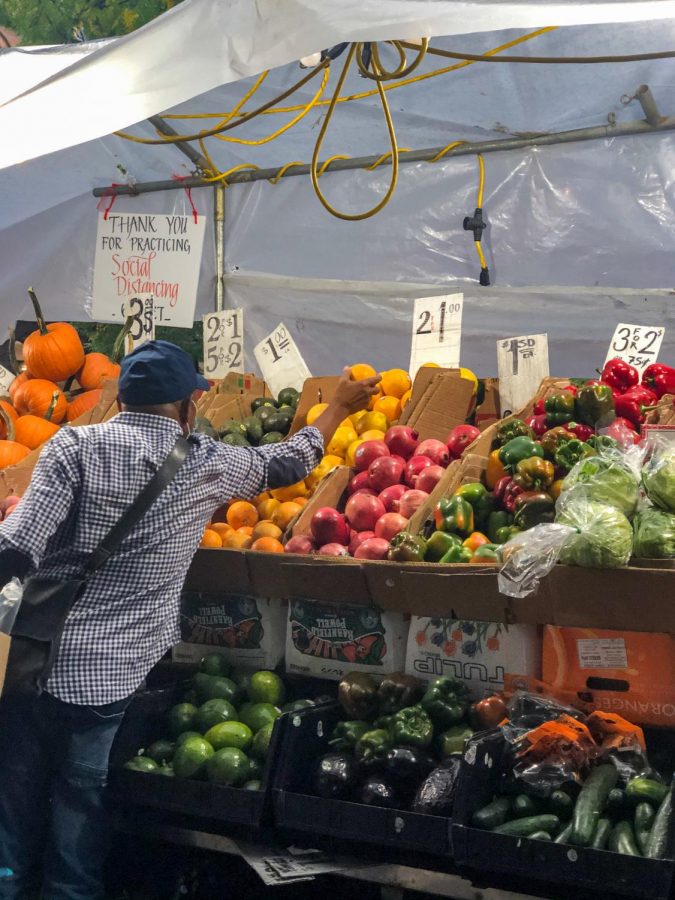 a man reaches to grab a piece of fruit from a produce stand
