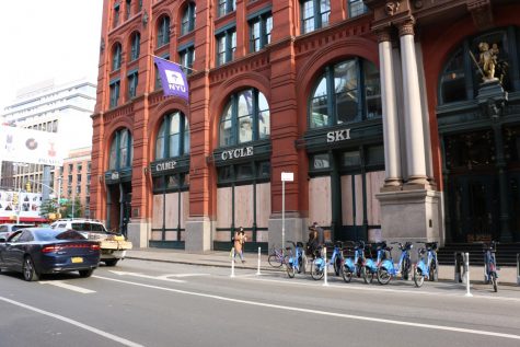 the boarded up REI store in Soho with a purple NYU flag flying above