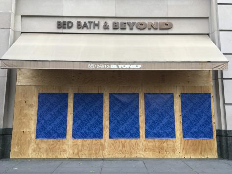 Bed, Bath, & Beyond with a boarded up storefront covered in branded posters for the store