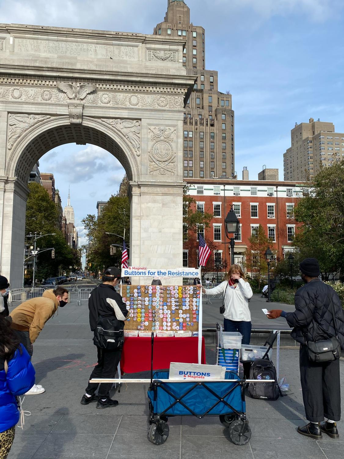 A button vendor in Washington Square Park with the Arch behind her