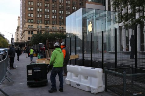 workers erect a fence in front of the Apple store