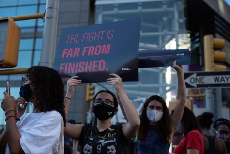 someone holds a sign at the celebration reading "The fight is far from finished"