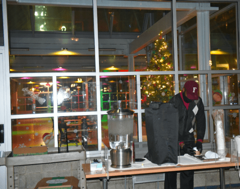 A Fordham employee serving hot chocolate and cookies at a table on the plaza