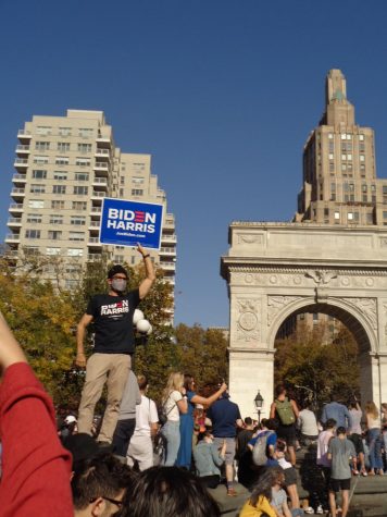 someone holds a Biden Harris sign in front of the Washington Square Arch