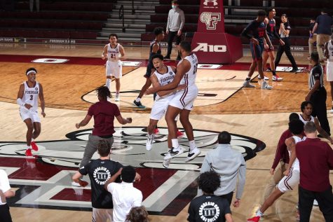 fordham basketball players jump and hug each other on the court after a win over dayton