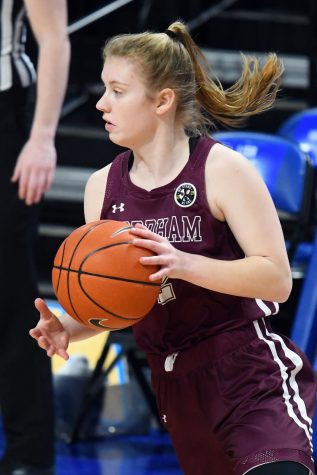 anna dewolfe in a maroon uniform holding a basketball and looking off to the side during the game against saint louis