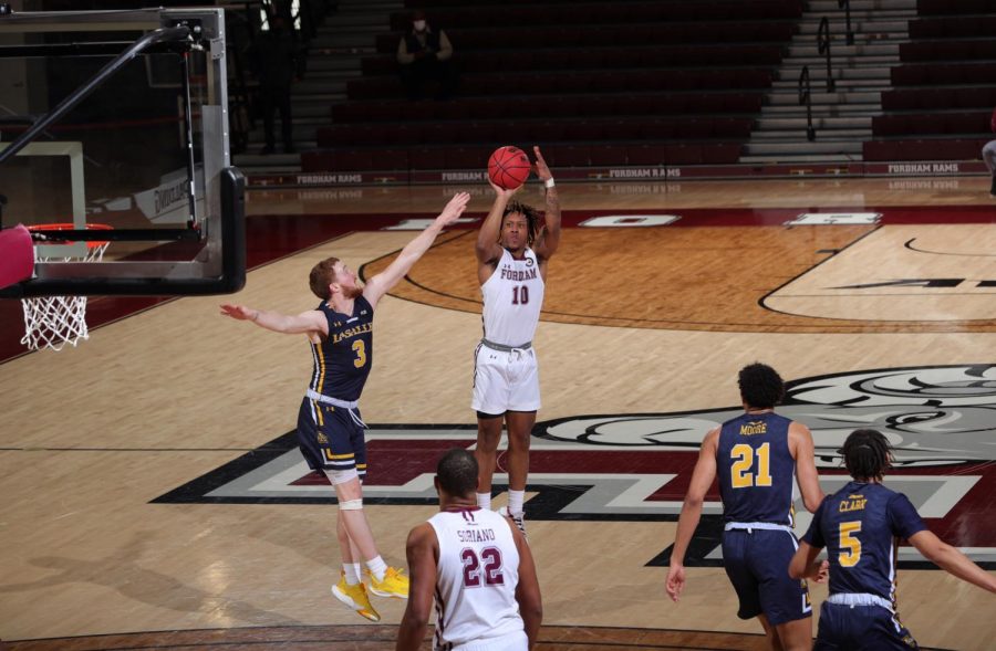 in+a+game+against+la+salle%2C+ty+perry+shoots+a+basketball+on+the+court.+he+is+wearing+a+white+uniform%2C+and+three+la+salle+players+in+navy+uniforms+are+around+him.+one+other+fordham+player+in+white+is+in+the+foreground