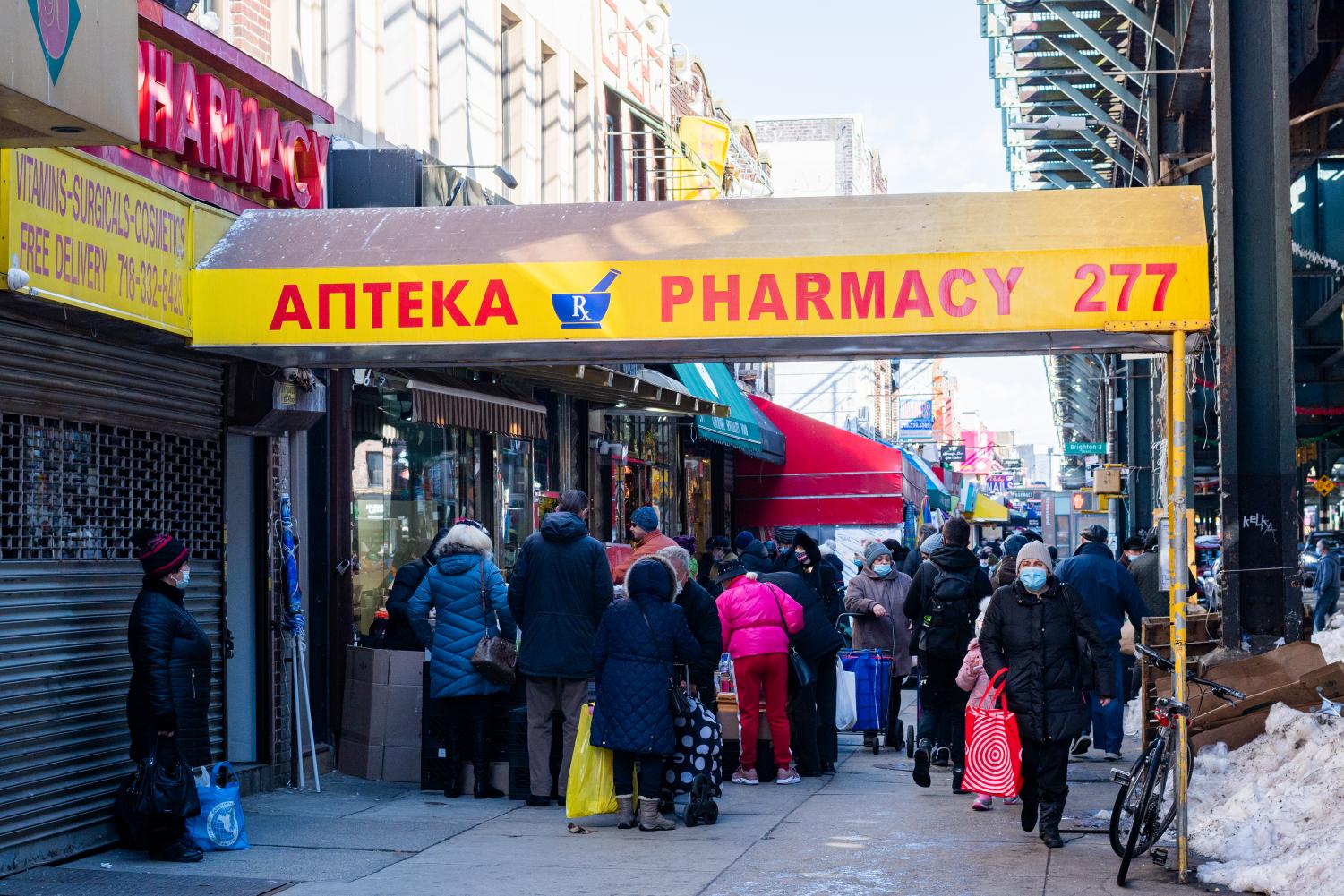 yellow awning of a pharmacy in little odessa, with a group of people standing in front of it