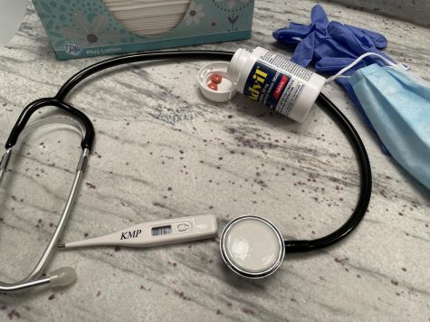 for an article about covid effects on the brain, photo of a stethoscope, a bottle of advil, gloves, tissues and a mask on a table