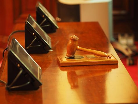 a gavel rests in front of screens on a courtroom desk