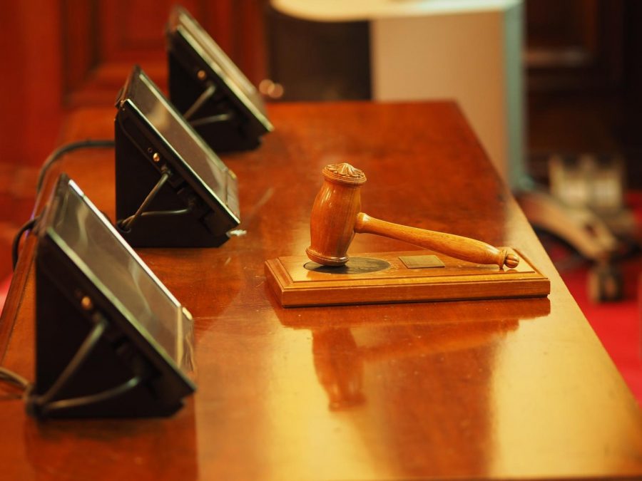 a gavel rests in front of screens on a courtroom desk