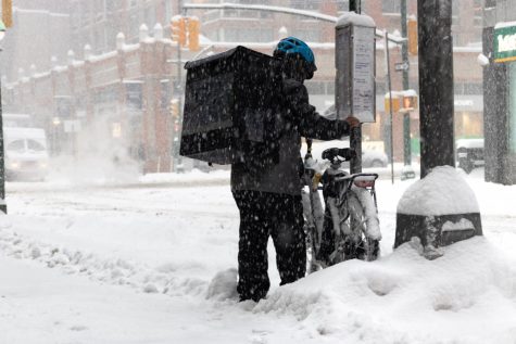 a delivery worker brushes snow of their bike