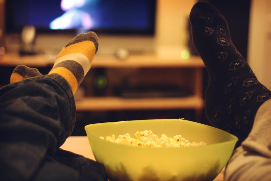 feet up on the table by popcorn with a movie playing on the tv