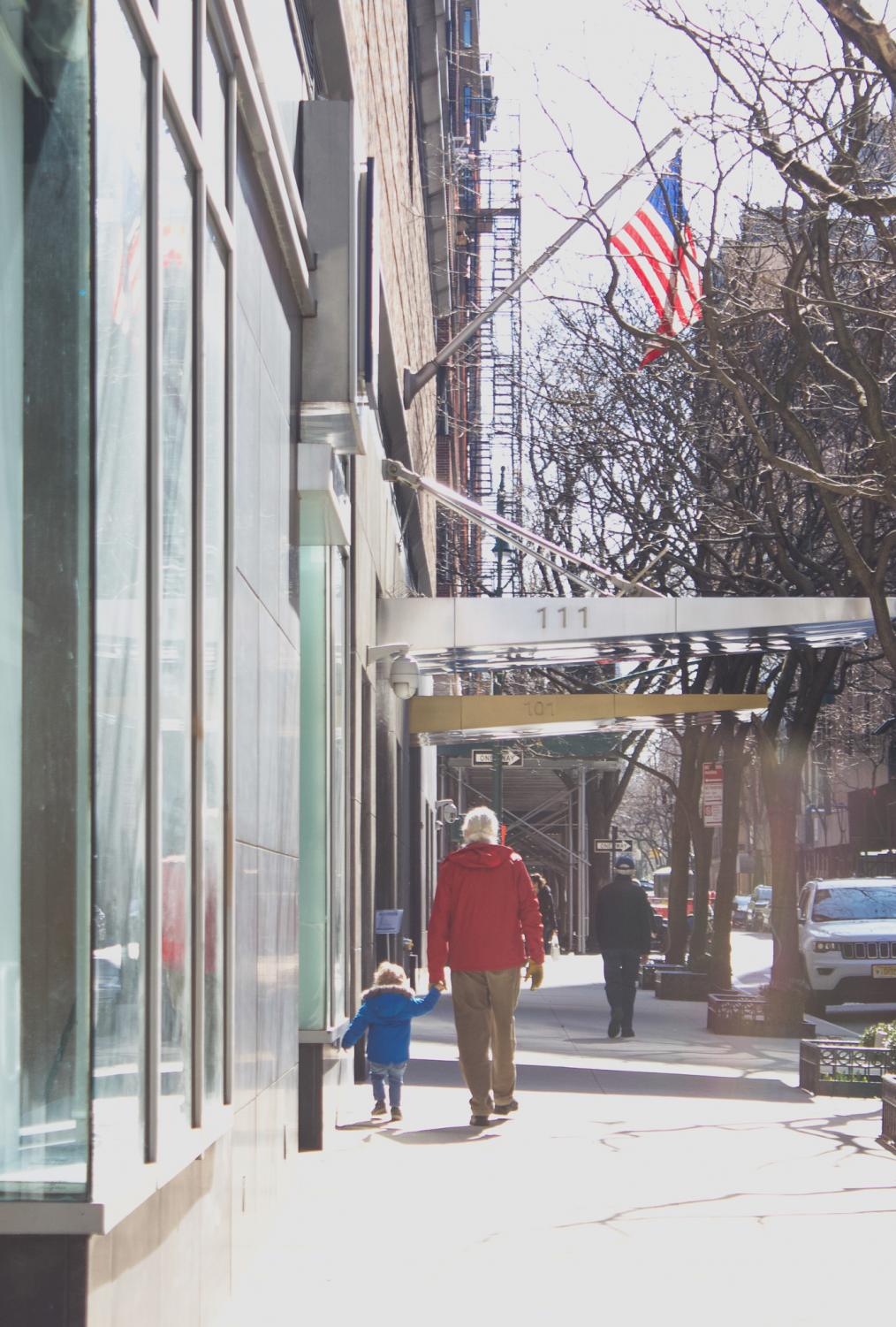 a parent and child walk on the sidewalk in spring