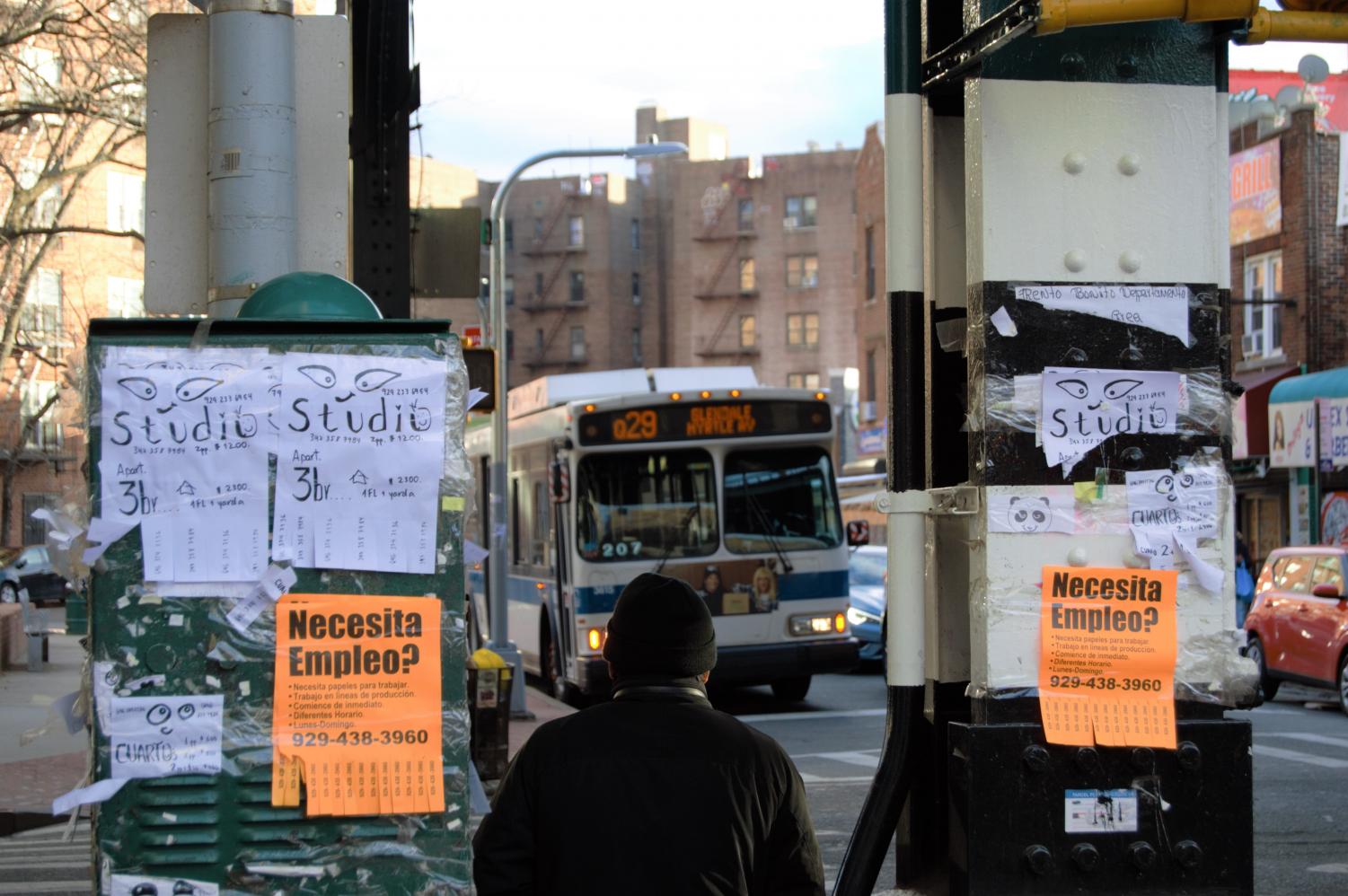 person on a jackson heights sidewalk with a bus in the background