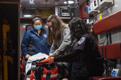 Three Fordham EMT students check a medical bag in an ambulance.