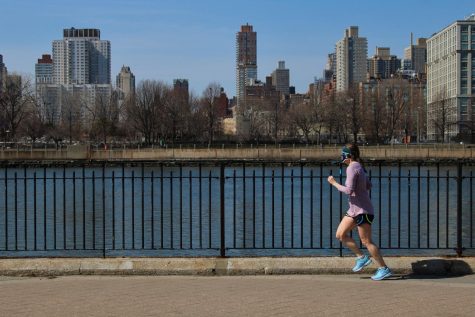 woman running in front of a body of water with a skyline in the background