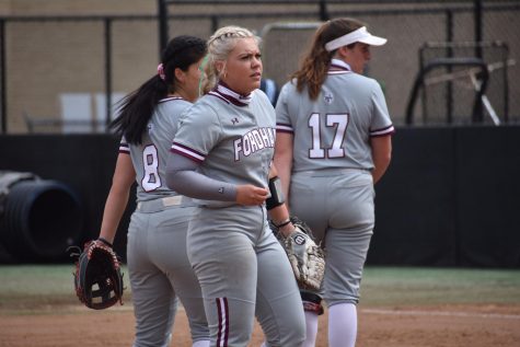 Fordham softball players stand on the field.