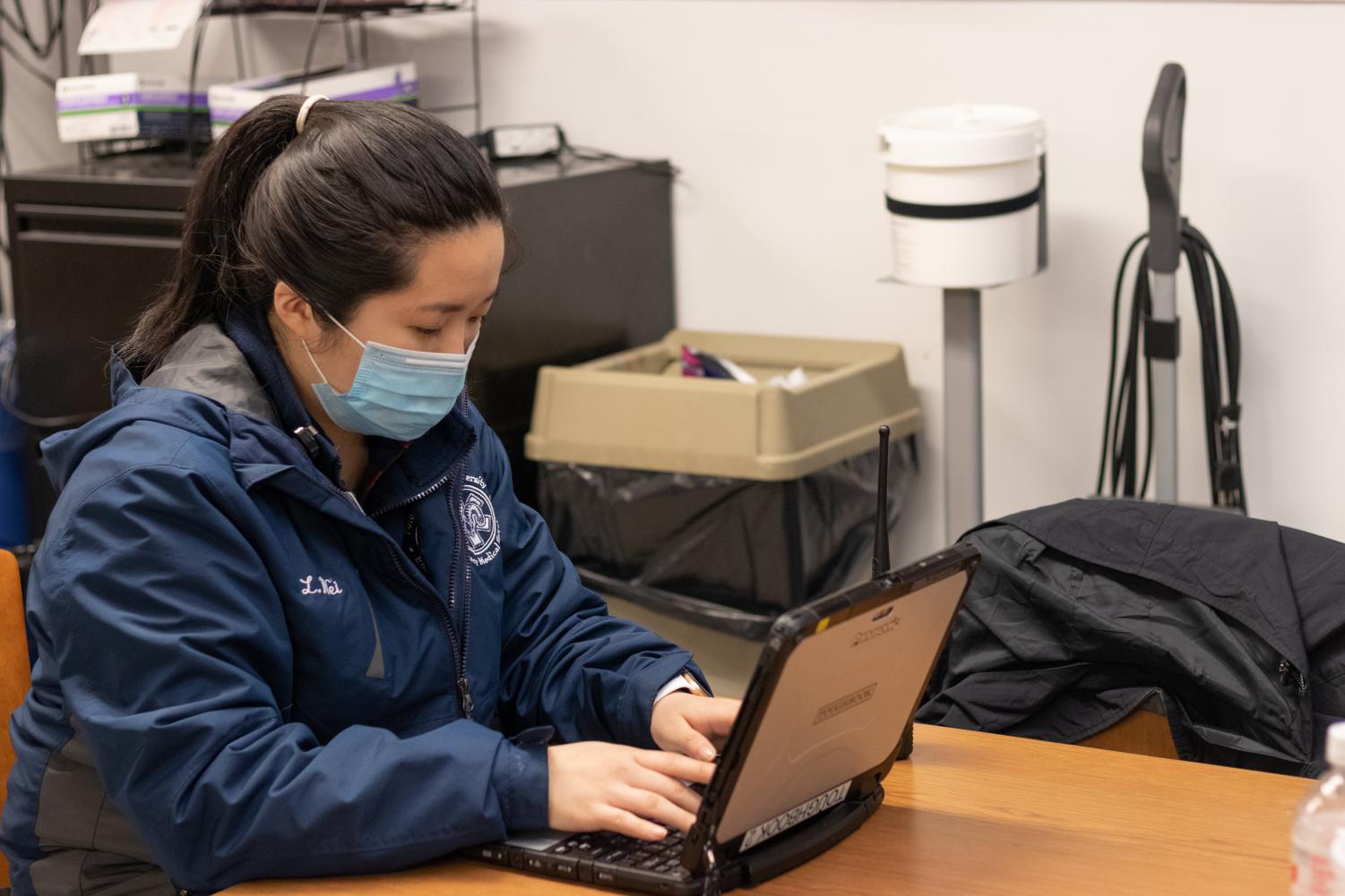 Li Ying Wei works on a laptop on her Fordham EMT job.