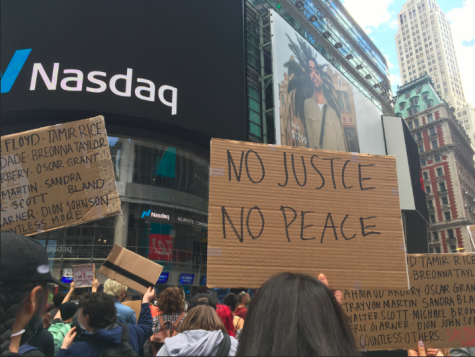 for an article about covid-19 photos, someone holds a sign reading "no justice no peace" in reference to the summer 2020 protests