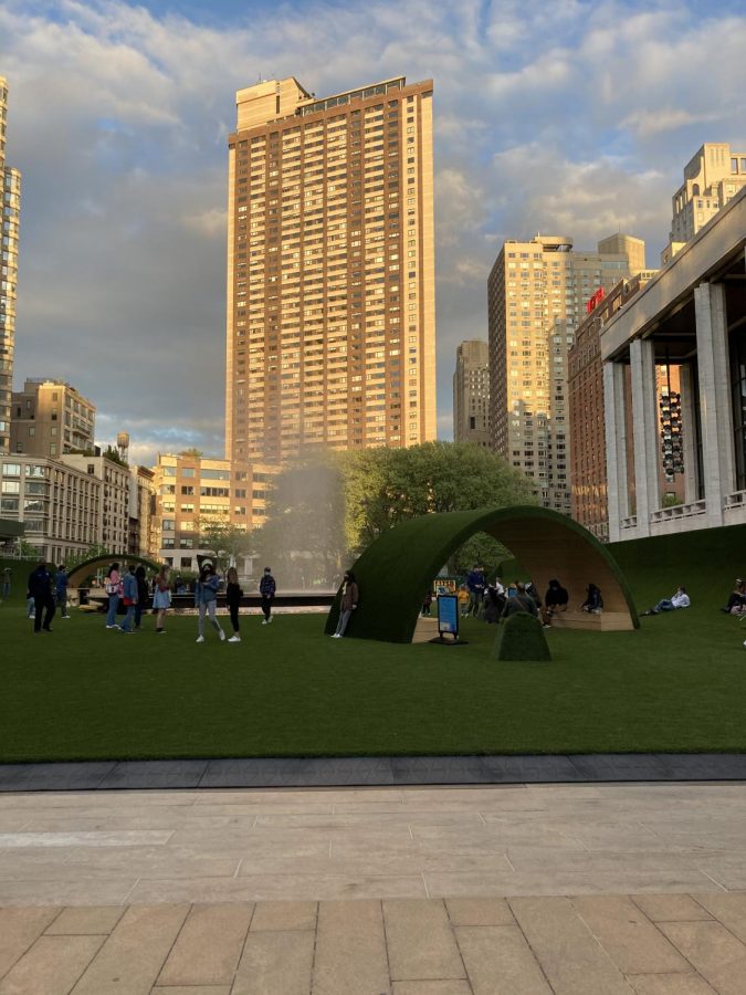 The GREEN's arches covered in synthetic grass stand in front of the city skyline.