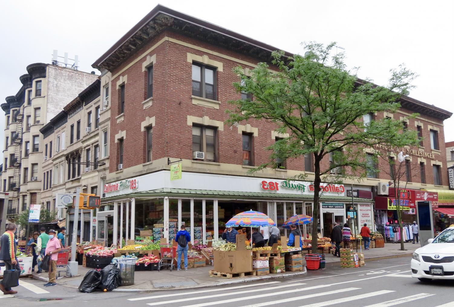 a street corner with boxes of produce surrounding a small food market